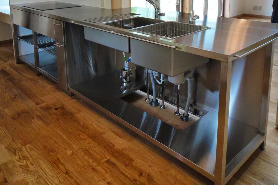 キッチンは業務厨房タイプのオープン、収納は木製キャビネットの実用重視